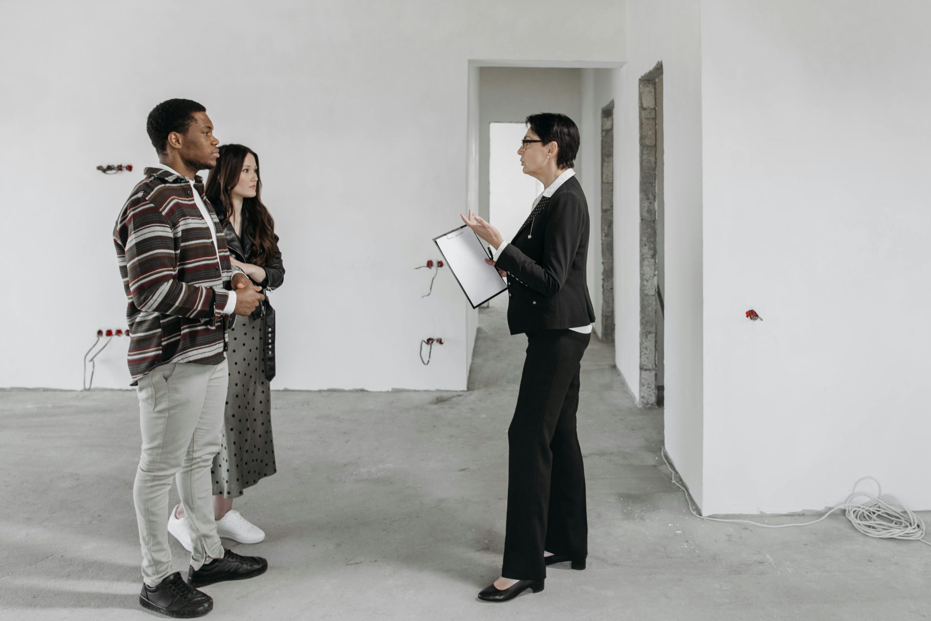 Real estate agent showing a house to a couple in a newly built home interior.